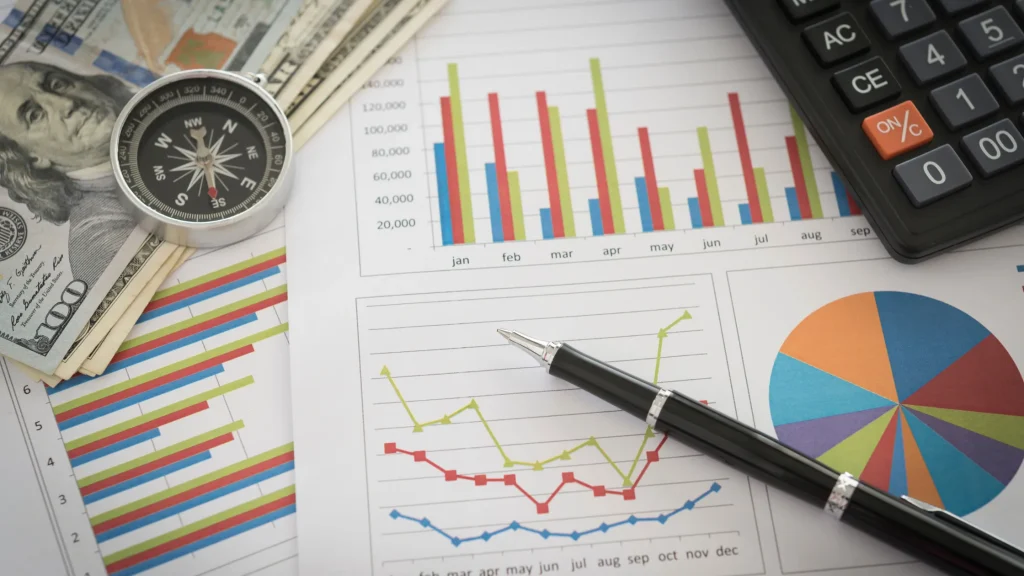 Financial documents with charts, graphs, a compass, cash, and a calculator representing SEO-driven data analysis for financial growth.